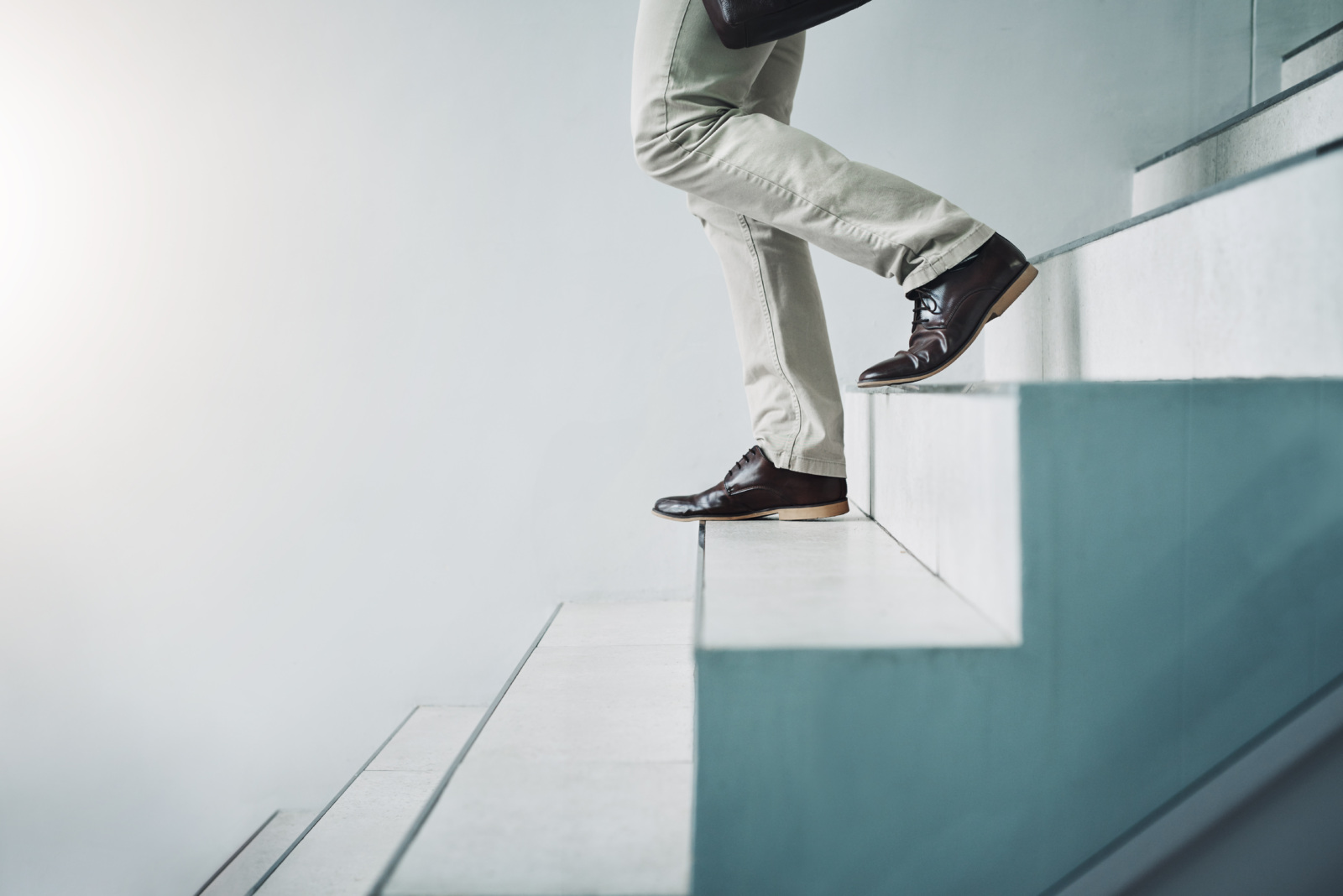 Closeup shot of an unrecognizable businessman walking down a staircase in an office