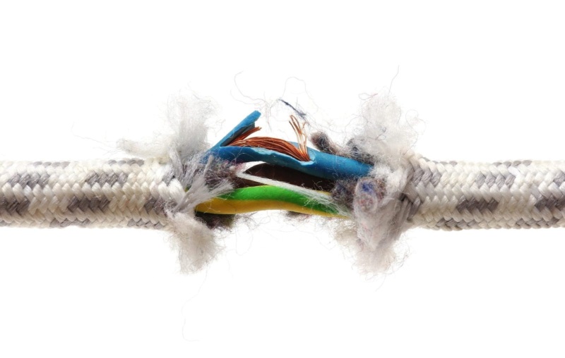 A close-up of a frayed electrical cord showing exposed and damaged wires.