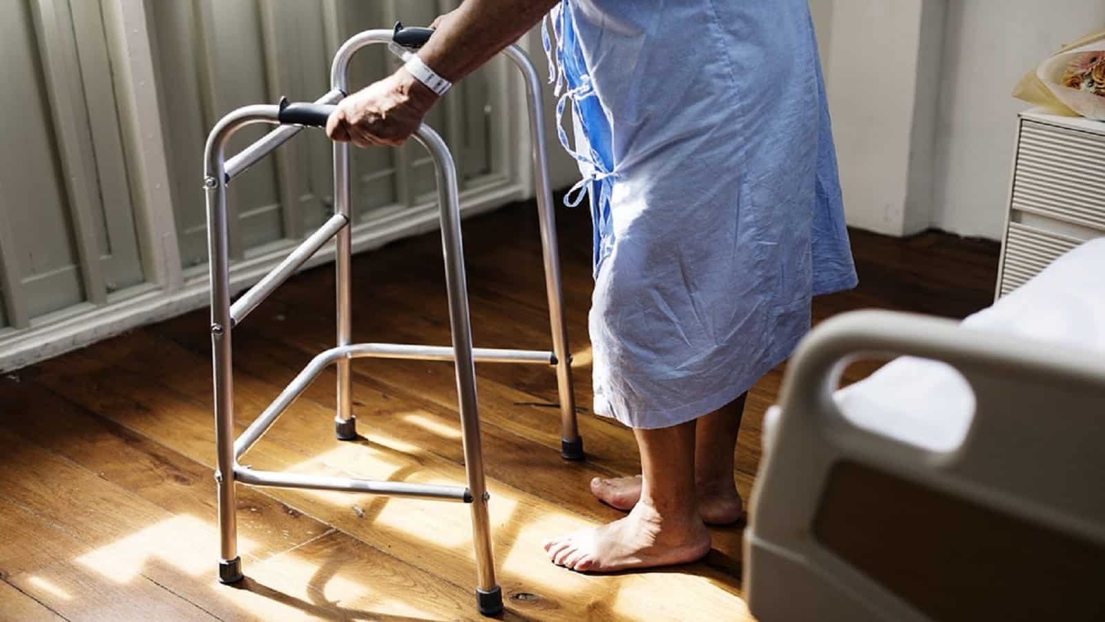 Elderly Woman Using Walker In Hospital Room Stock Photo