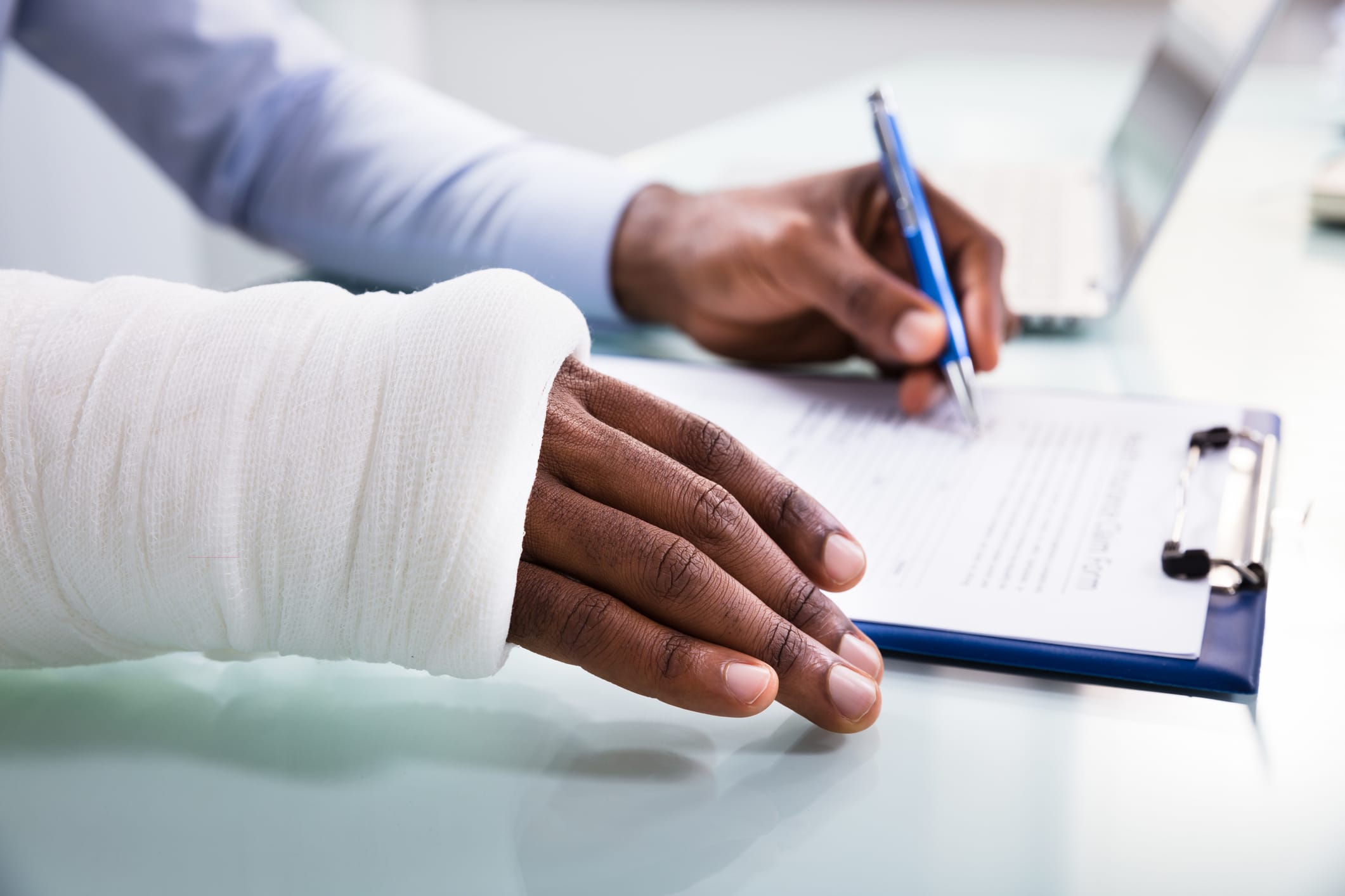 A person with a broken arm filling out a personal injury claim form