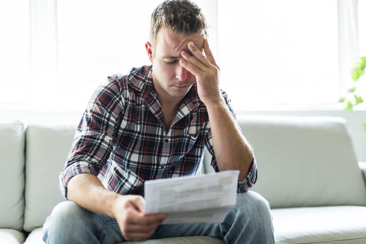 A man feeling stressed looking at bills after a personal injury