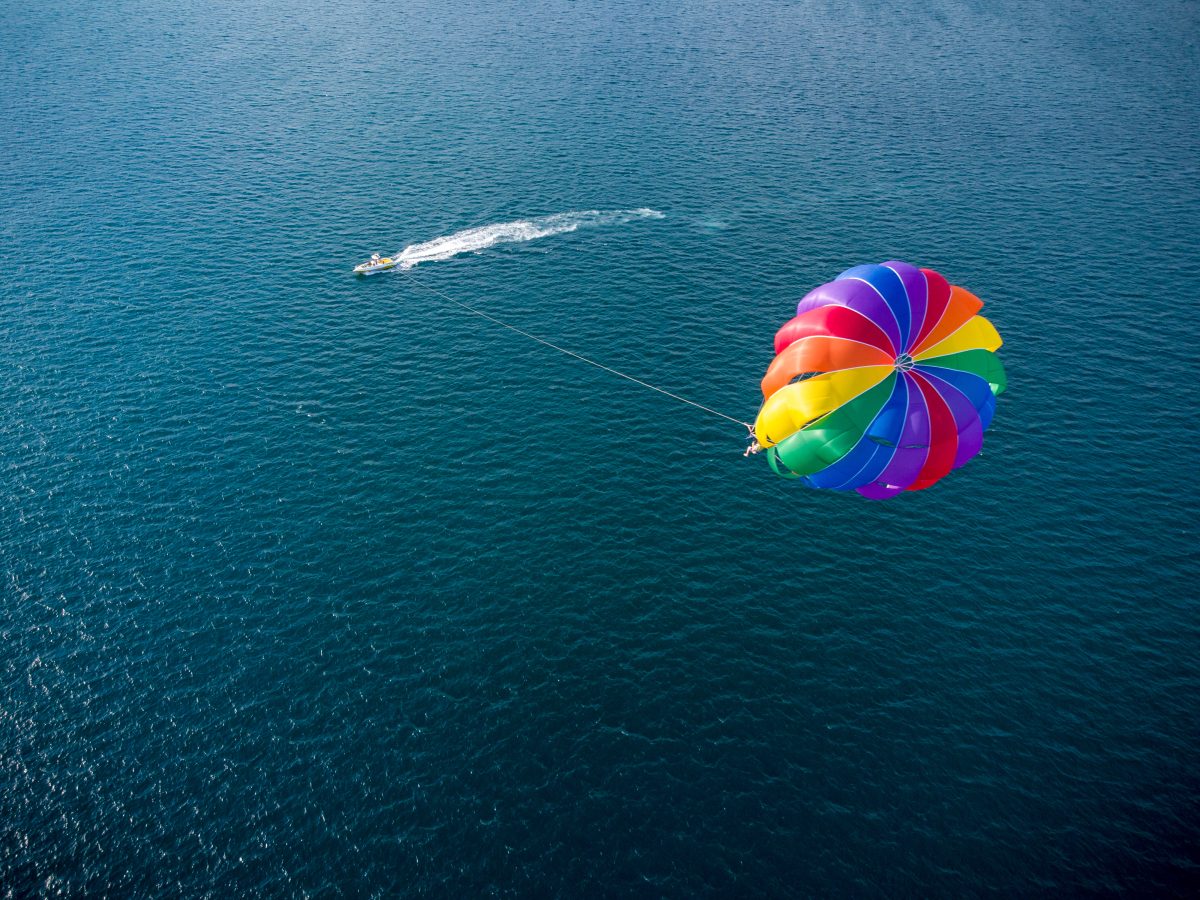 A tow boat is seen pulling along a person who is parasailing.
