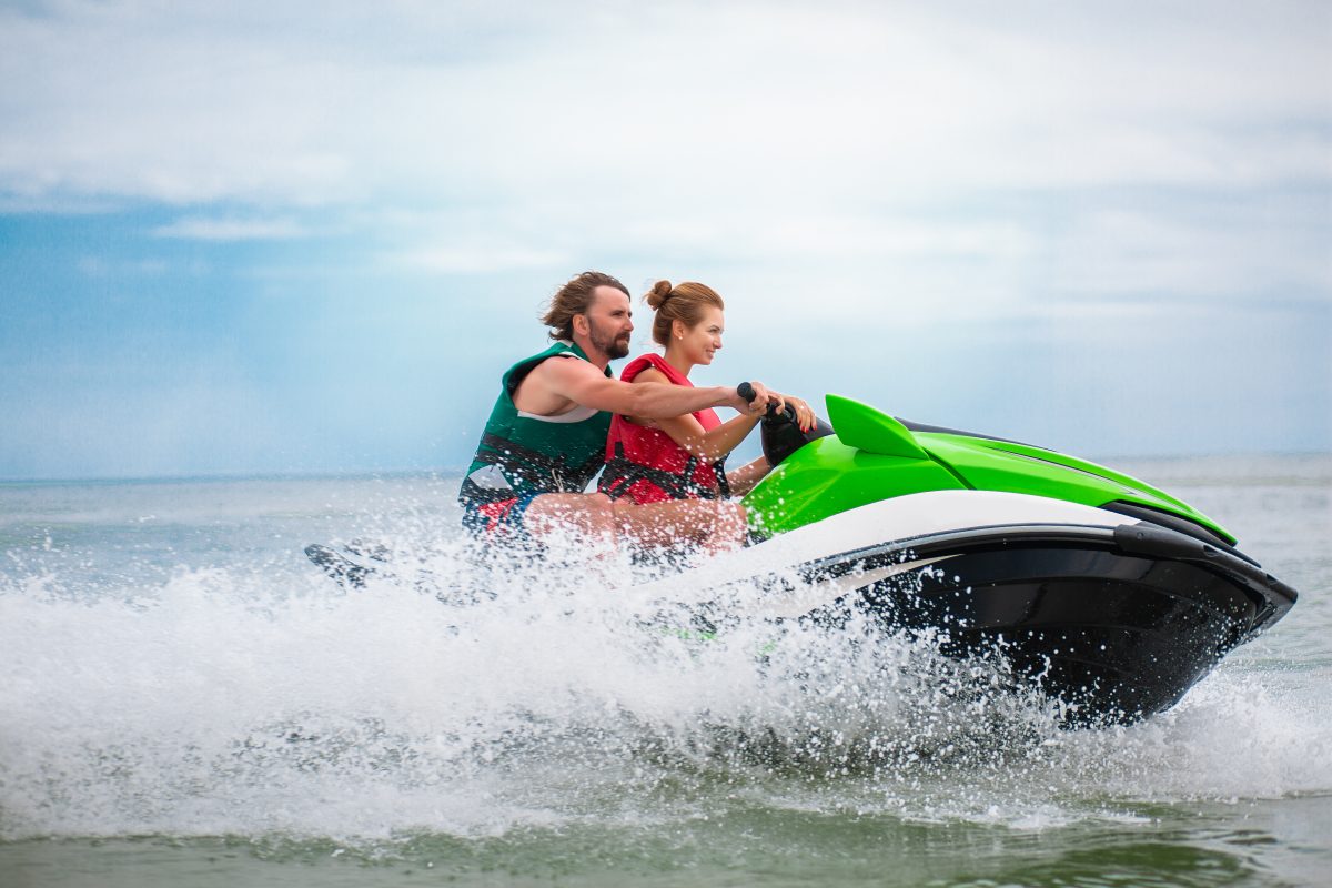 A couple rides on a WaveRunner® while wearing life jackets.